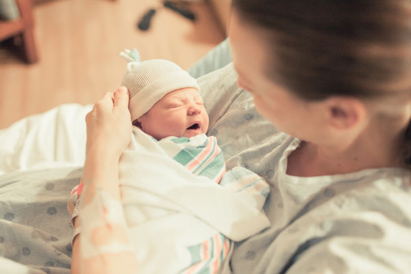 woman holding newborn baby in hospital
