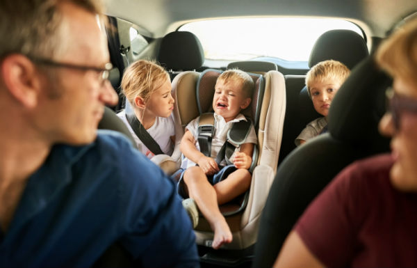 toddler having temper tantrum in car with siblings