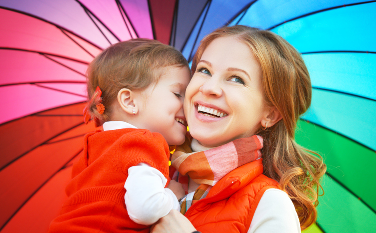 mom under rainbow umbrella holding her baby boy