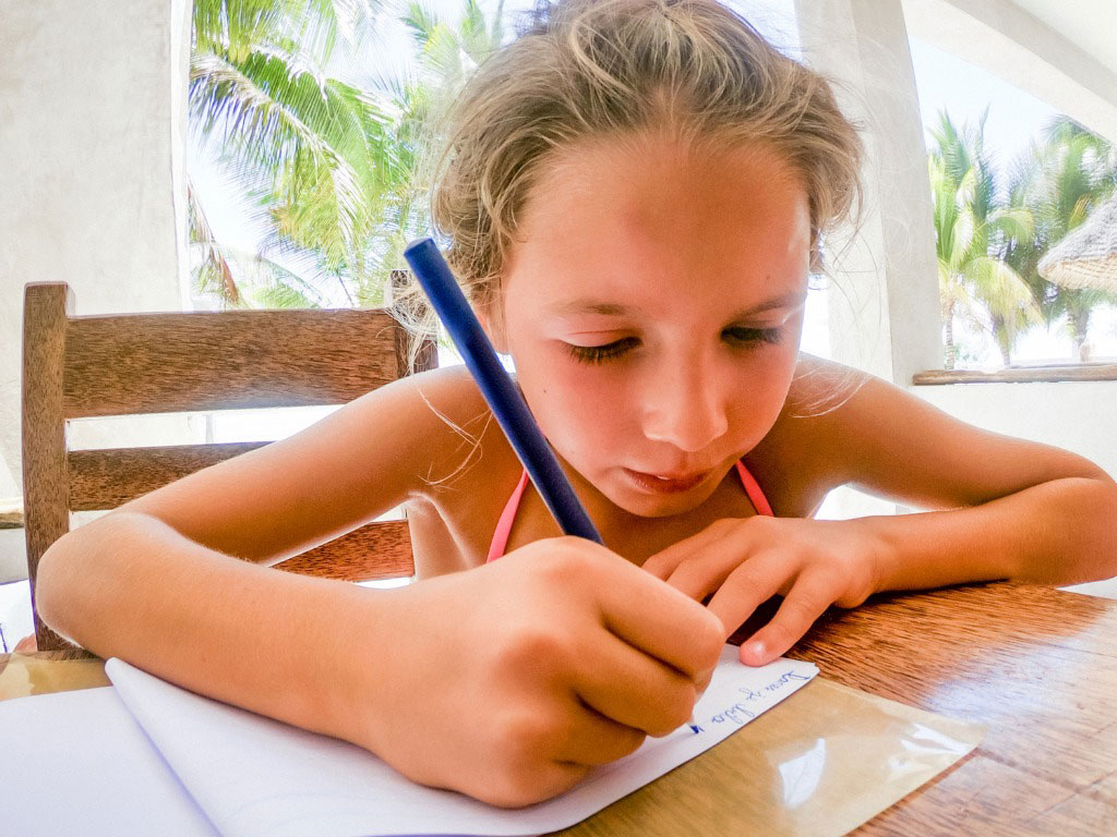 young girl writing in travel journal
