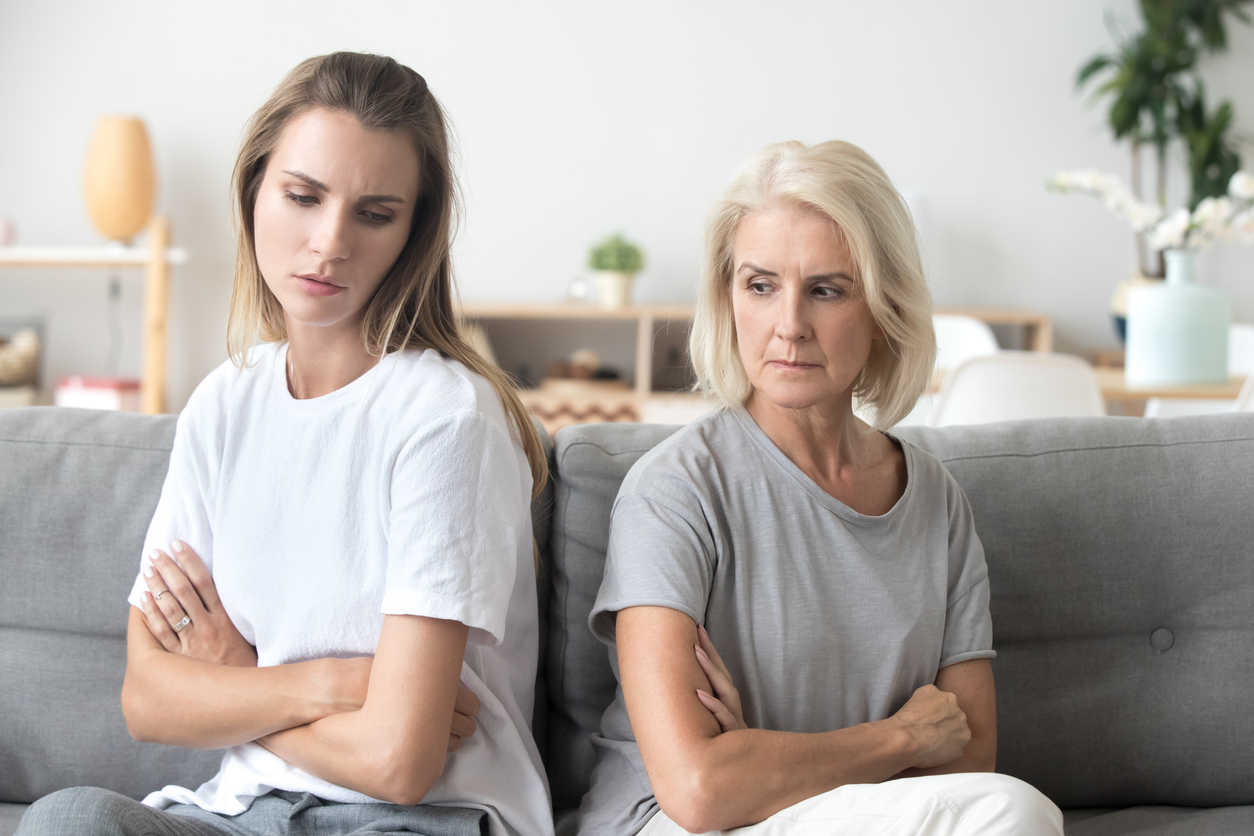 Upset older mother in law and adult daughter sit back to back not talking after fight disagreement