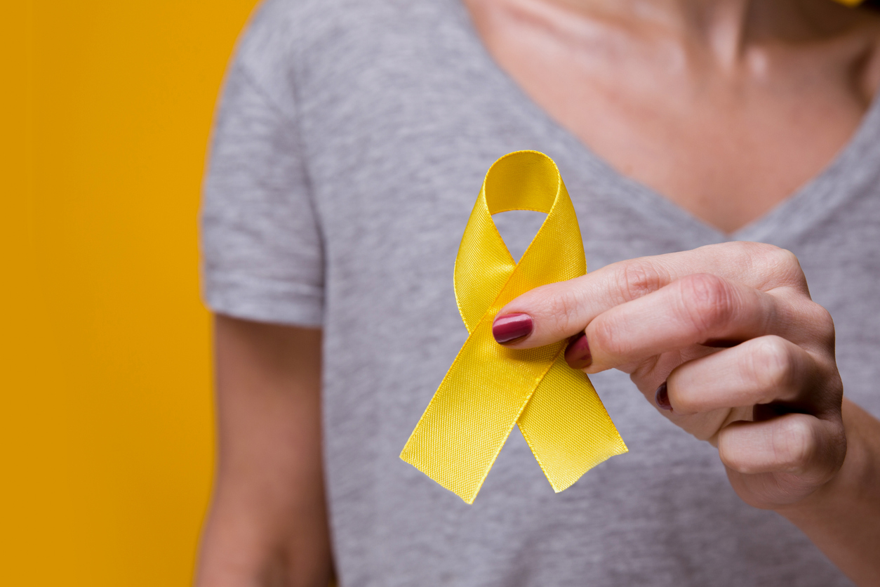 Young female holding yellow gold ribbon awareness symbol for endometriosis