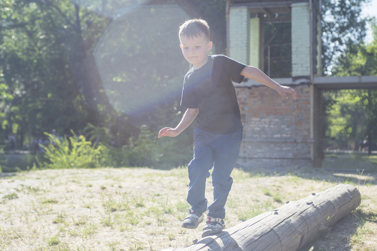 Little boy walking on a log in the park