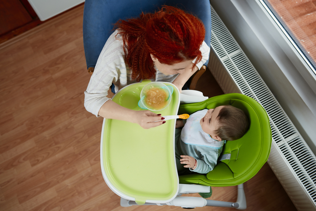 high angle view of mother feeding her baby girl indoors. lifestyle shot.
