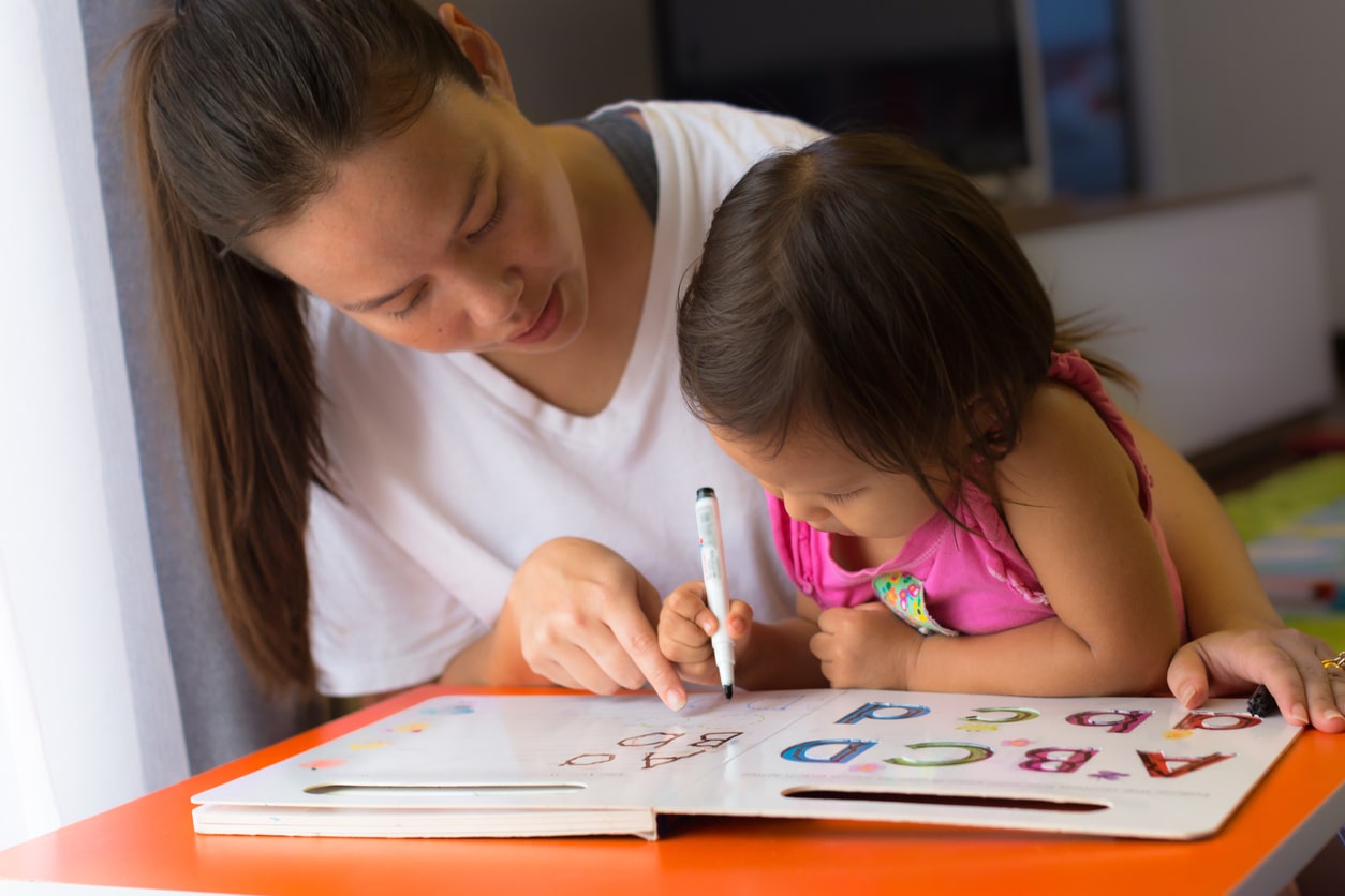 A mother teaching her child how to write her name before Kindergarten