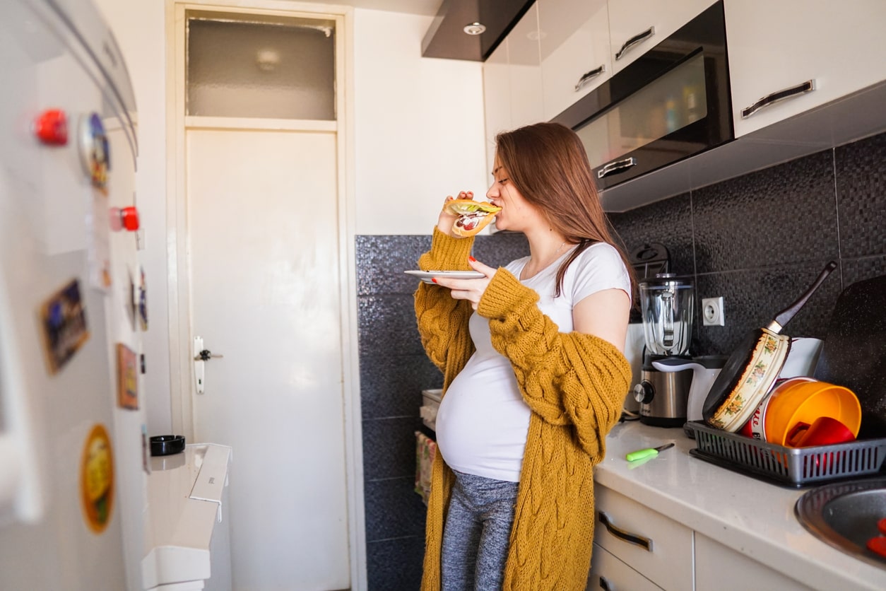 Pregnant woman suffering from Hyperemesis Gravidarum (HG) eats small meal in the kitchen