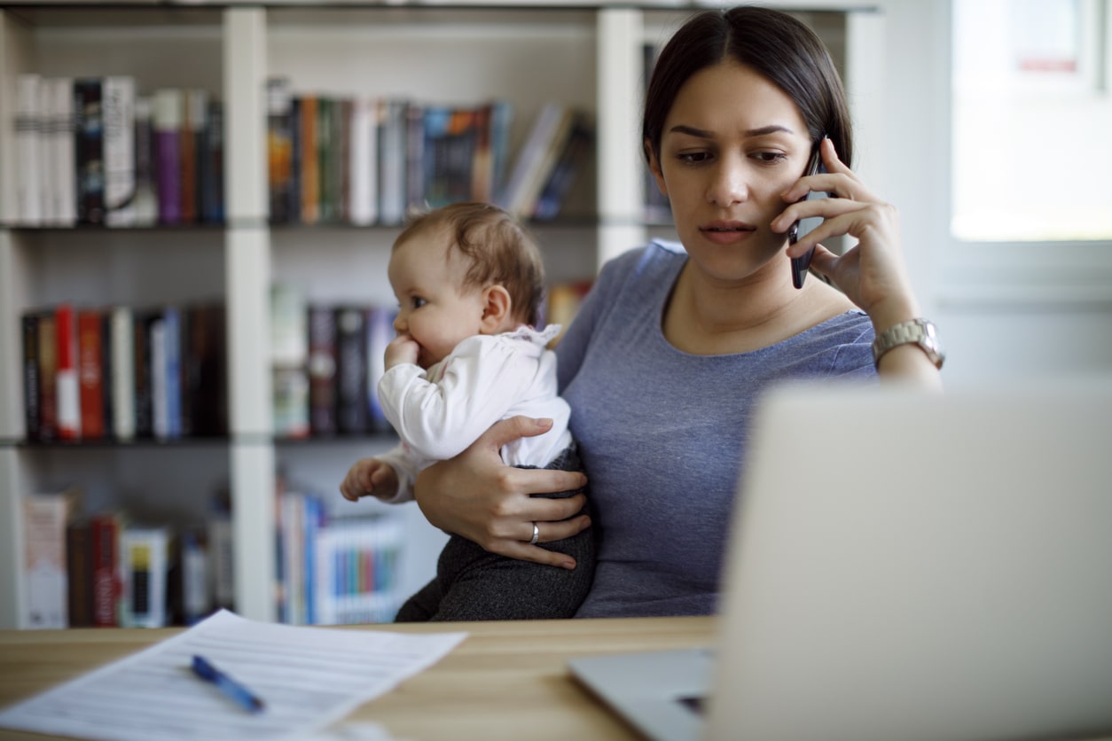 New mother works from home with baby daughter on her lap