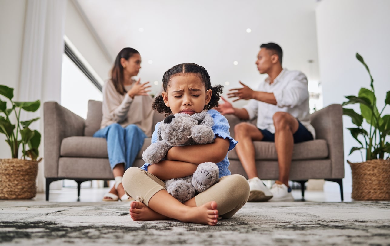 Parents, fighting and sad girl in living room with teddy bear for support or comfort. Family, divorce and husband in argument with wife and scared kid sitting in fear, stress or depression on carpet