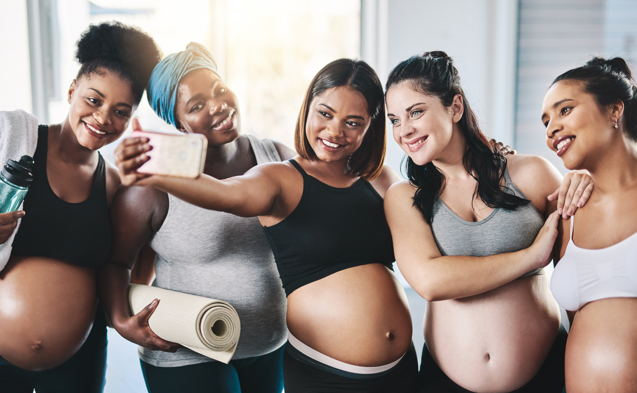 group of pregnant woman attending prenatal yoga class. taking a pre-class selfie