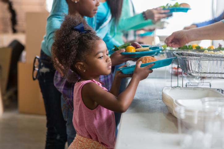 young girl getting food at a soup kitchen 