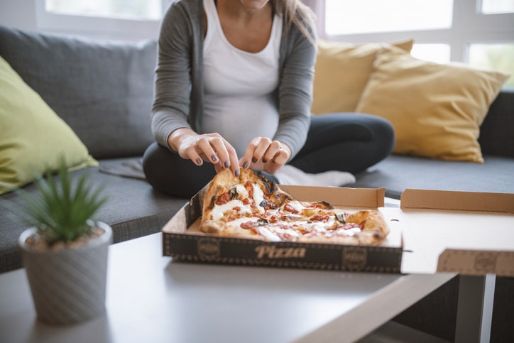 Pregnant woman eats pizza at home