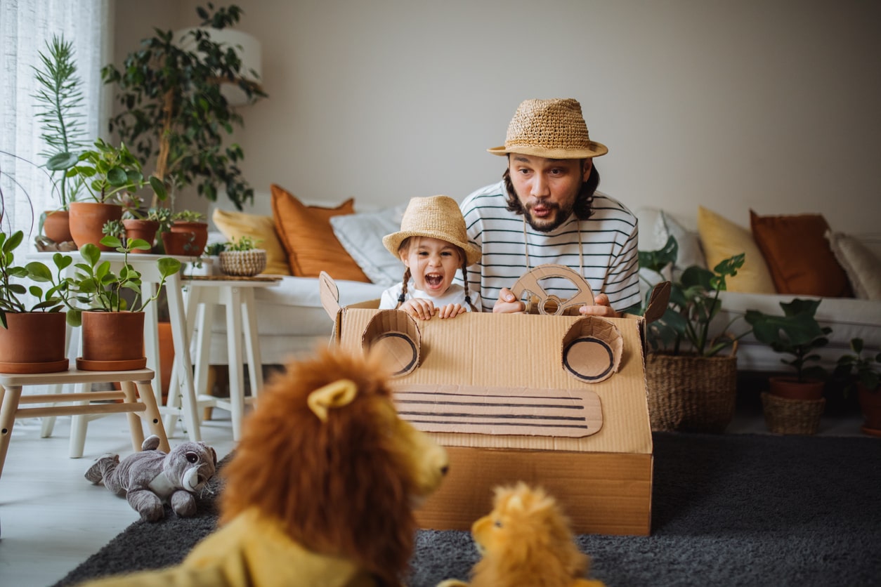 Father and daughter play pretend safari in their living room.