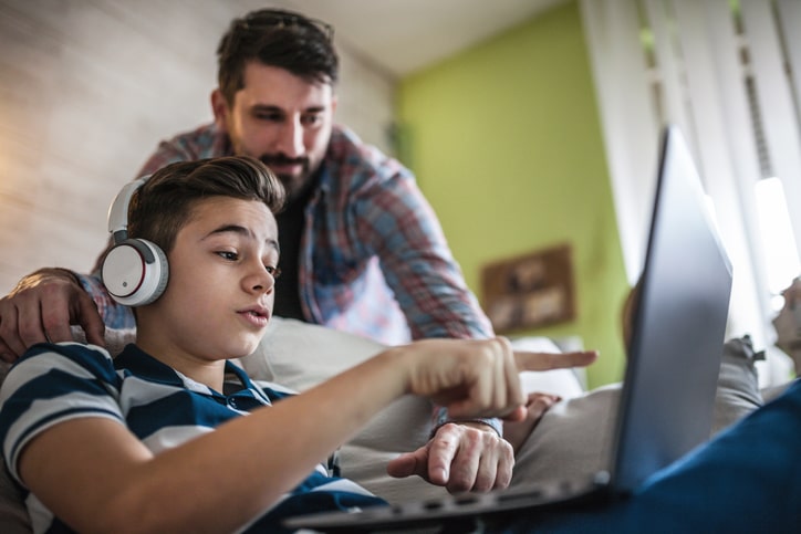 Father and son sit together on the computer