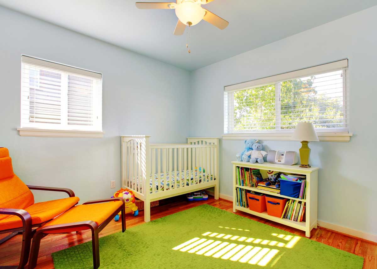Baby nursery room design with green rug, blue walls and orange chair