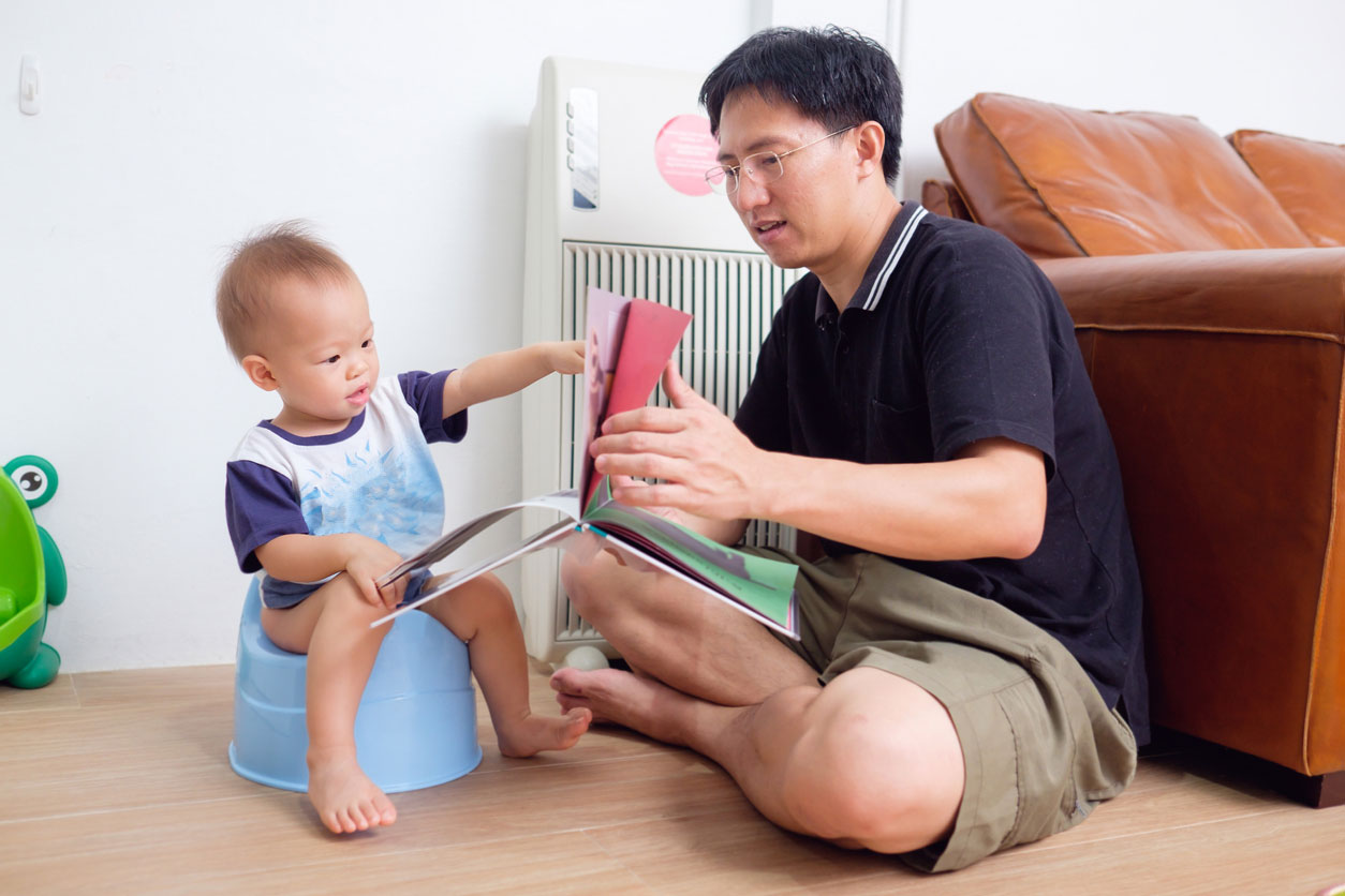 father potty training son with book