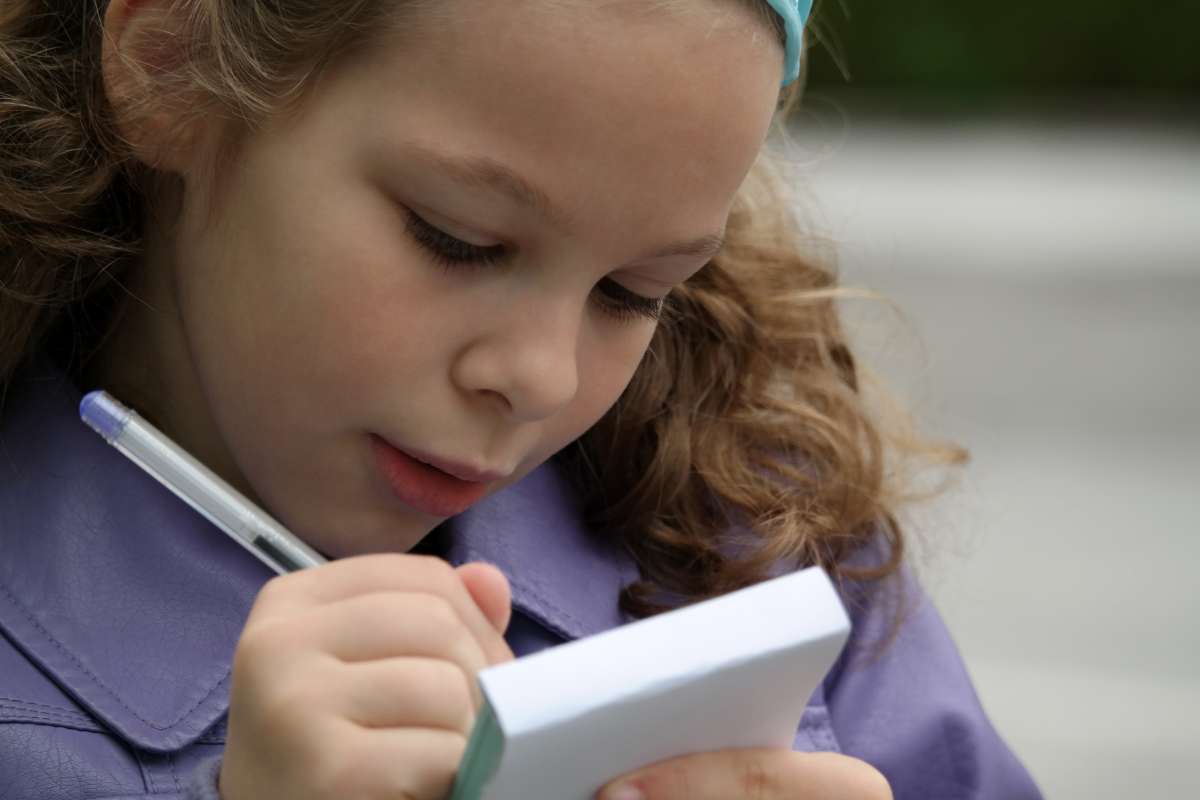A child writing down her findings for her invention