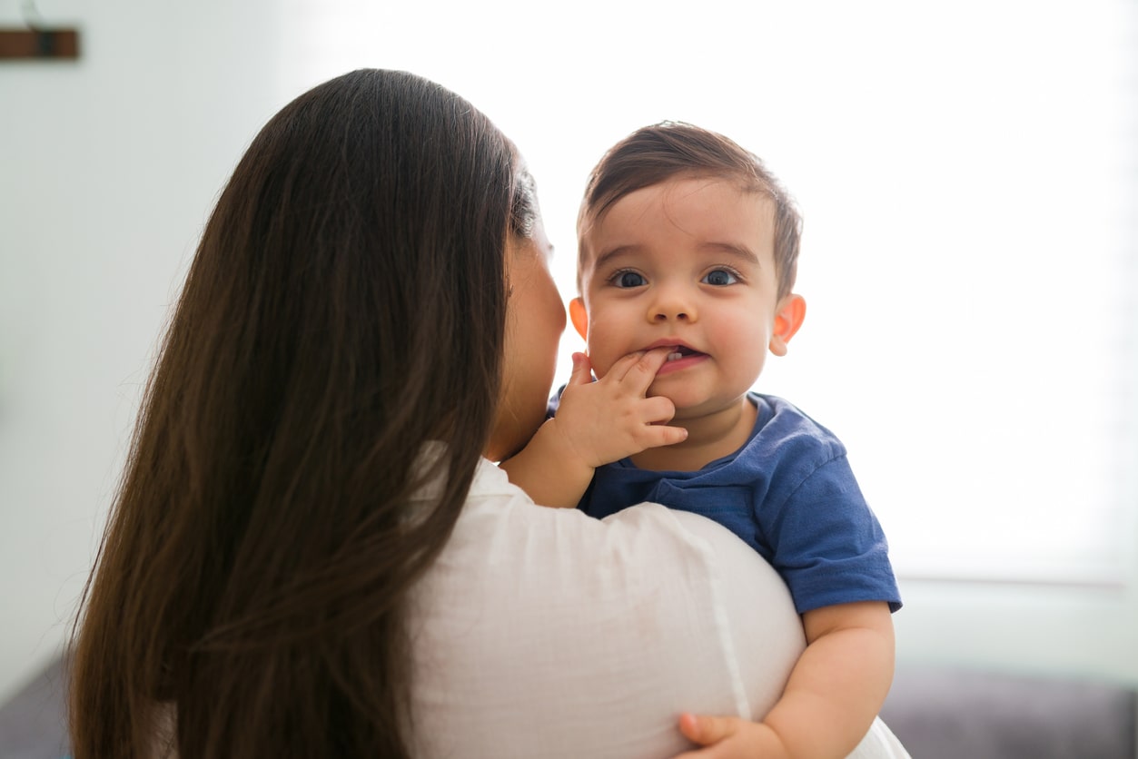 Toddler is teething as mother holds him. Toddler teething tips.