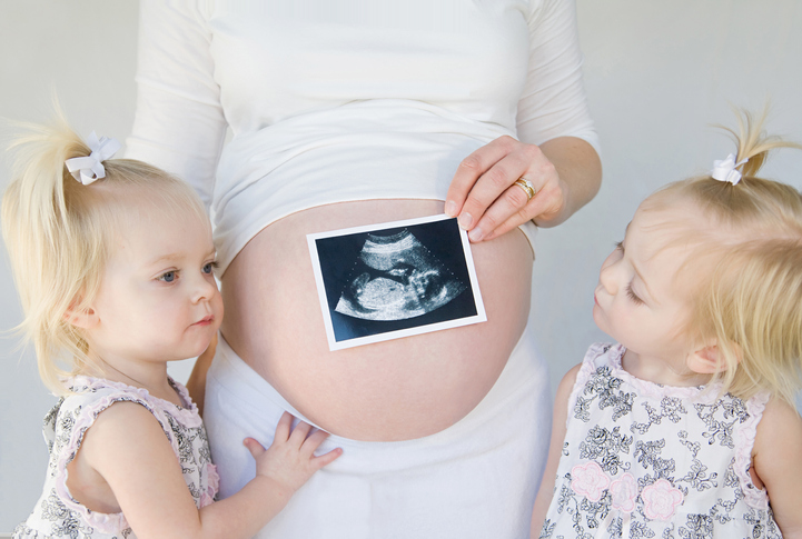 Twin Girls with a pregnant mother holding a sonogram 