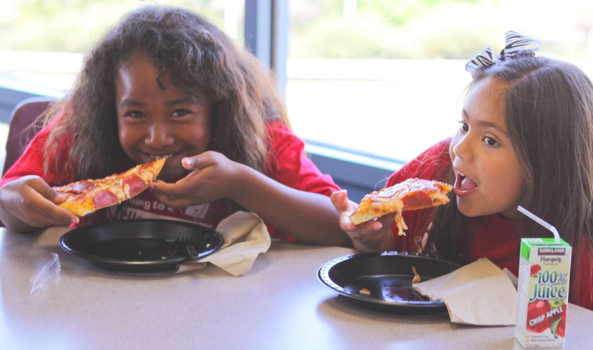 Two Young Girls Eating Pizza