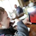 child using ipad while dining out