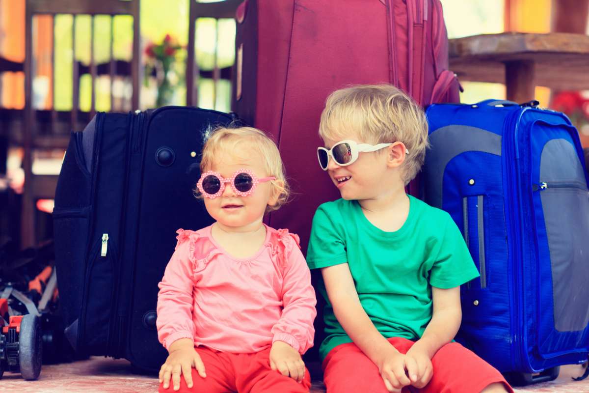 kids with fully packed suitcases ready for family vacation