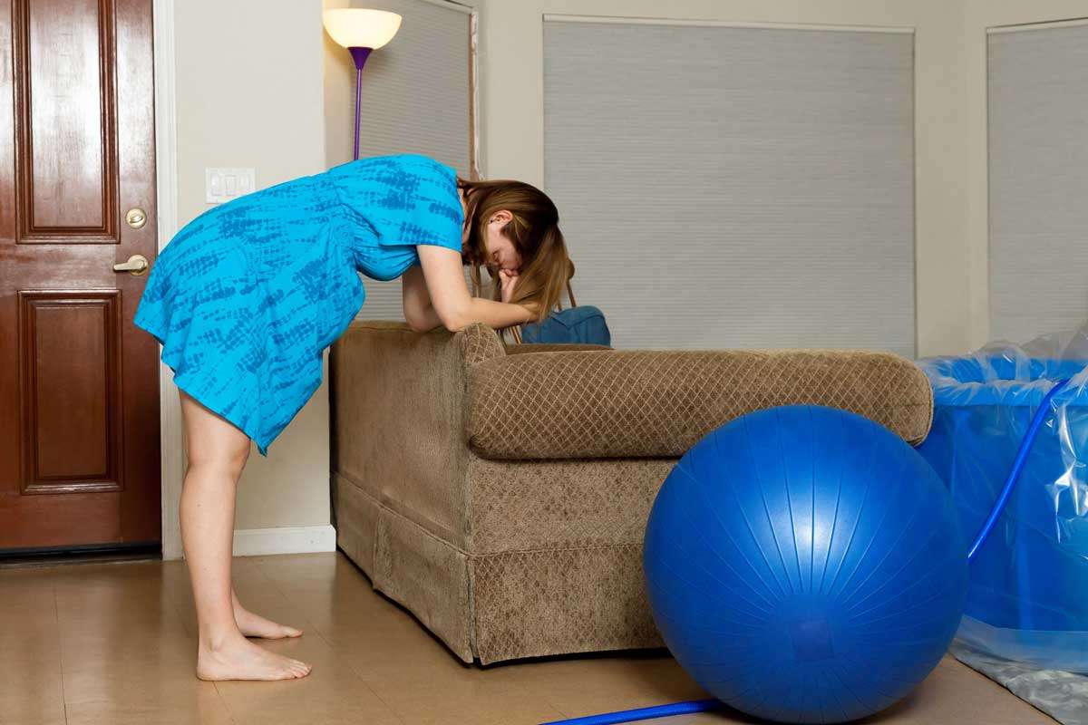 Pregnant woman leaning forward on couch