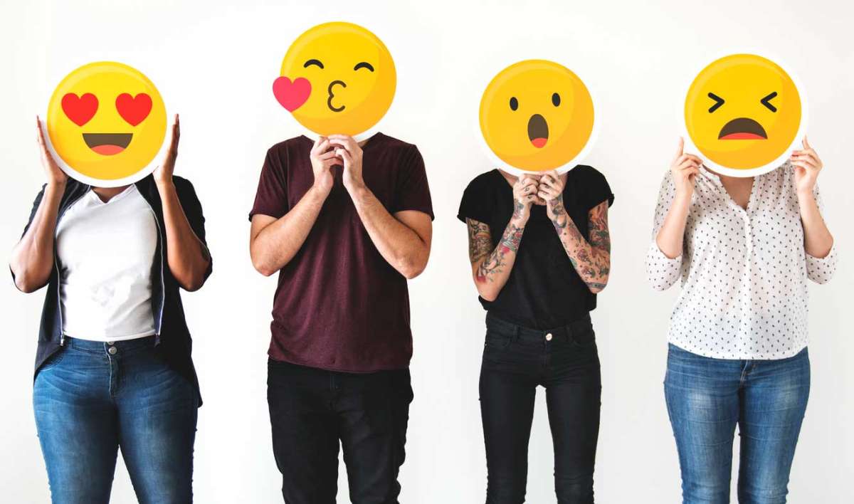 Diverse people holding emoji masks over face