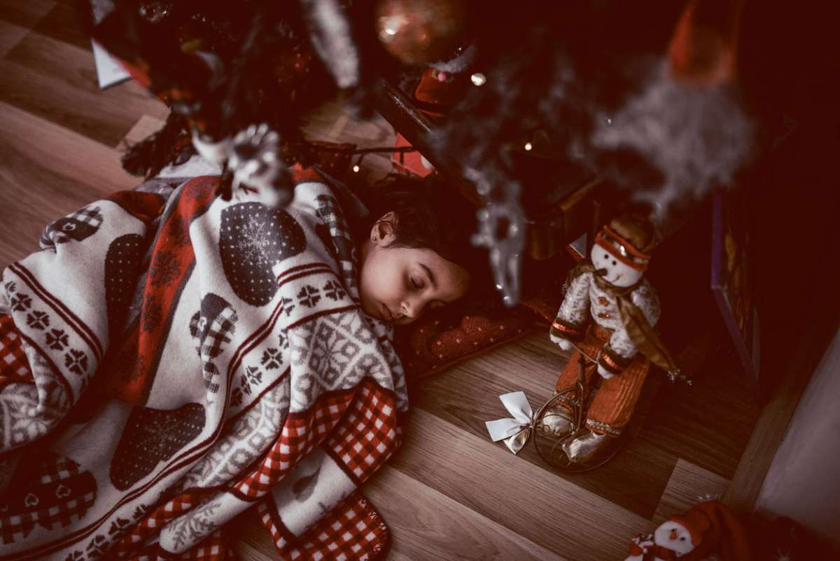 little girl sleeping under tree on christmas morning