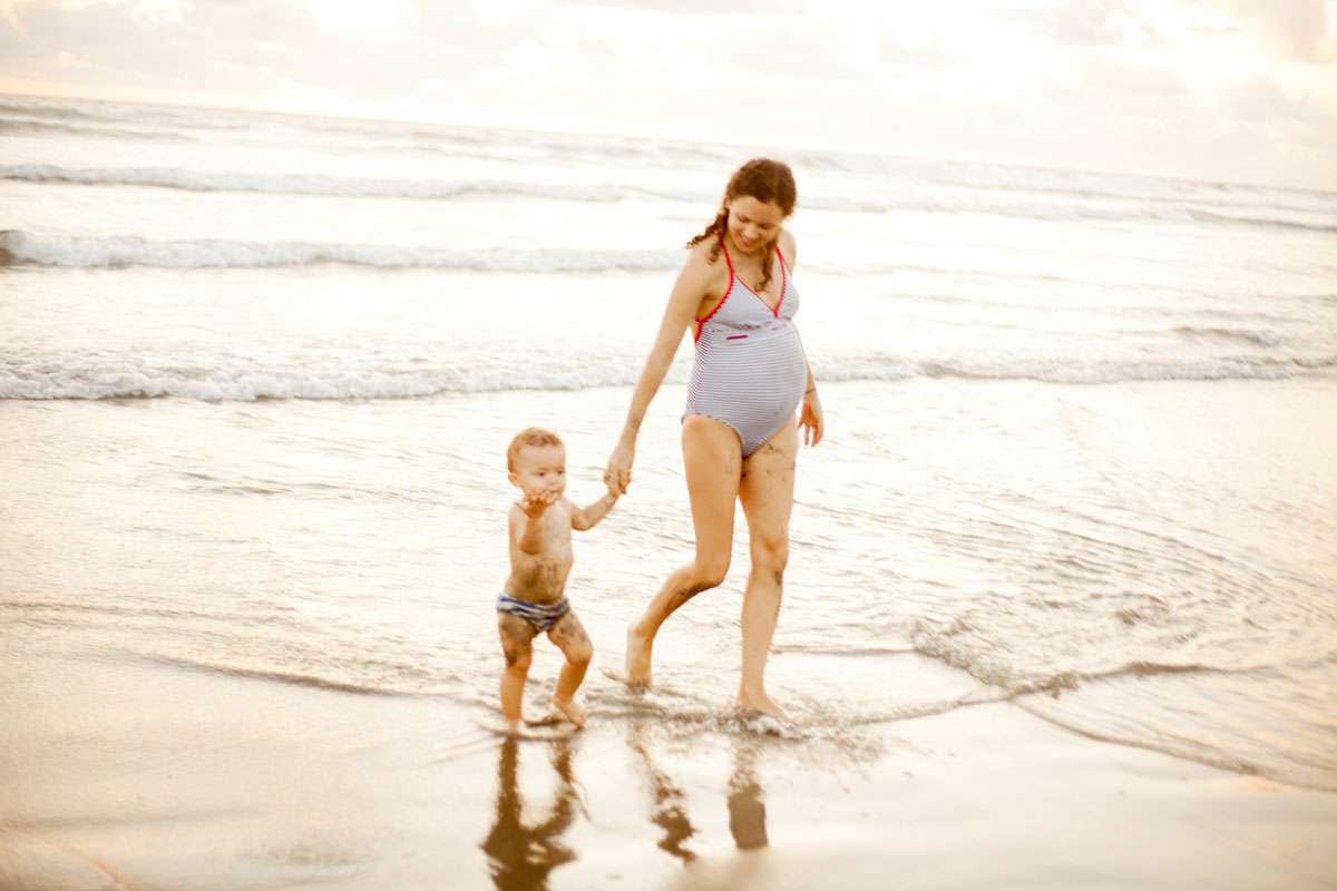 Pregnant woman playing with her son on the beach