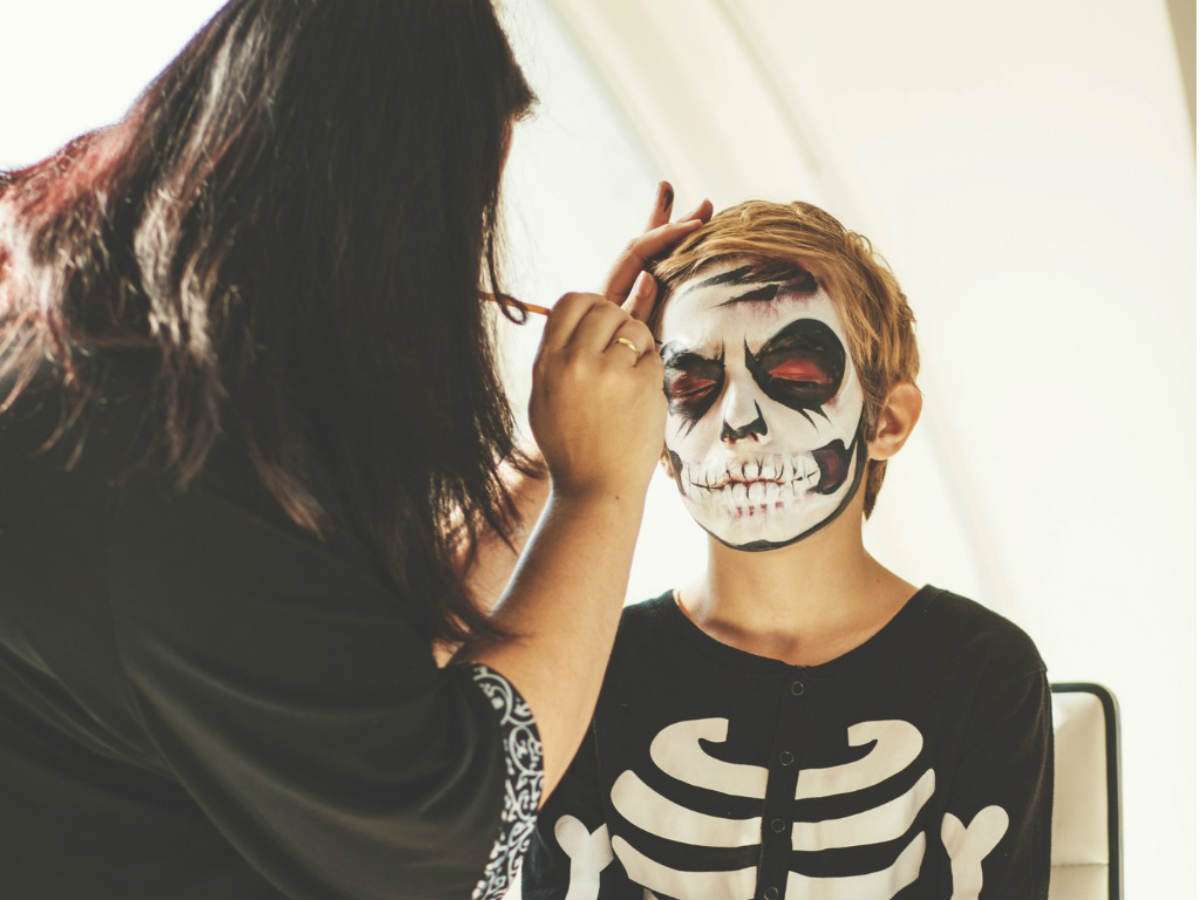 woman applying halloween makeup on kid