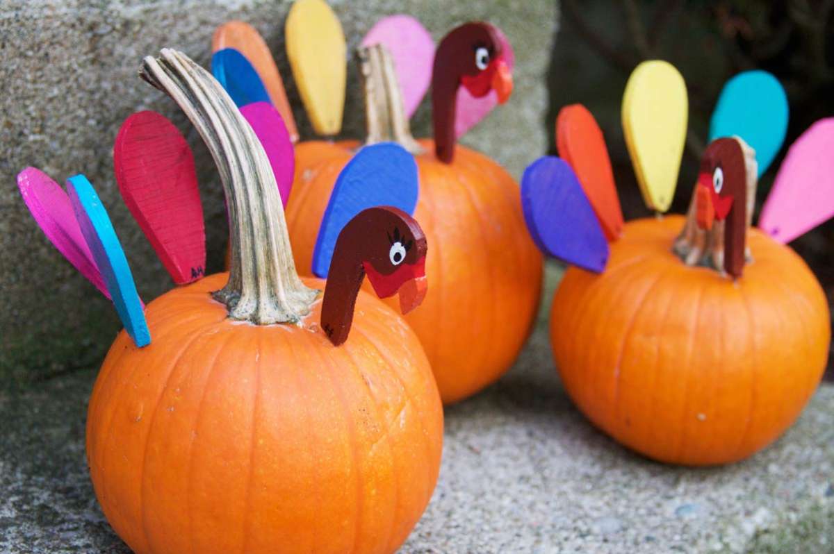 3 pumpkins decorated to look like turkeys for Thanksgiving kids table