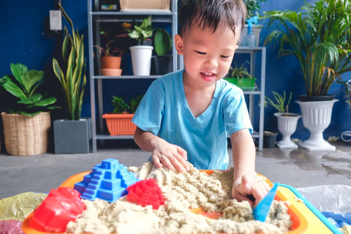 Asian 3 - 4 years old toddler boy playing with kinetic sand in sandbox at home, Fine motor skills development