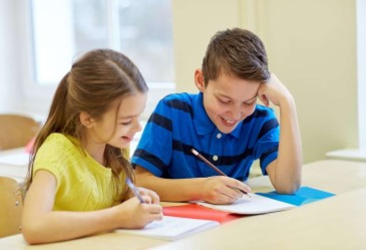Two Smiling Students Writing in Notebooks