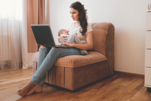 mom breastfeeding baby looking at laptop