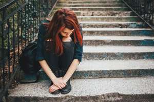 Burnt out teen girl sitting alone on outside steps