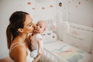 Mother tenderly holding newborn baby girl with popular 2019 baby name