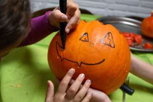Halloween safety tip, child drawing on jack o lantern