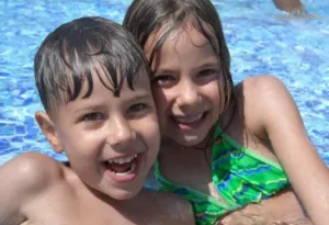 Two kids smiling in outdoor pool