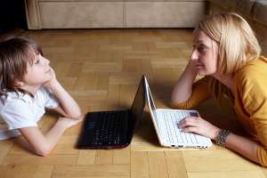 Mother and son facing each other using laptops