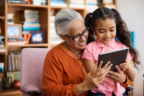 A child playing on an ipad with her grandmother