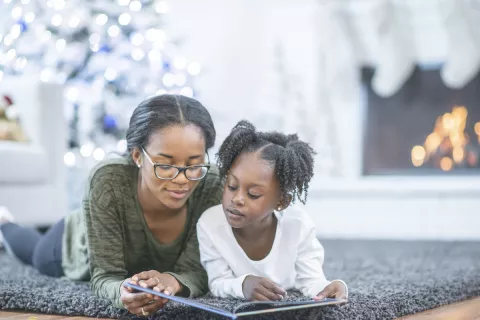 Mom reading kwanzaa book to her daughter