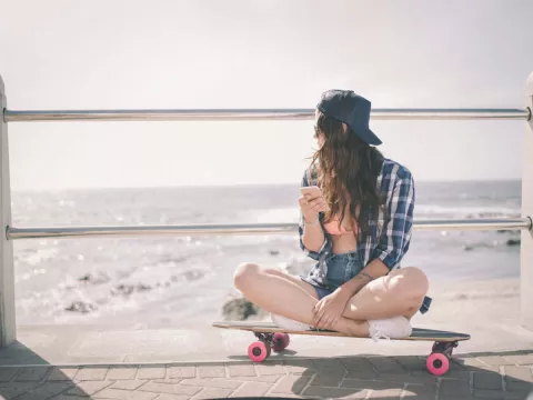 VSCO girl teen on skateboard at beach