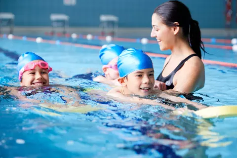 swimming coach giving lessons to kids