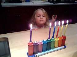 girl lighting menorah