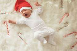 baby wearing santa hat in bed of candy canes
