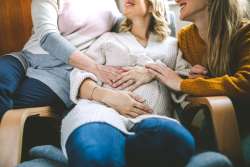 parents and pregnancy surrogate holding pregnant belly