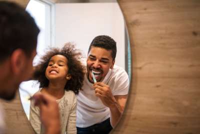 dad and daughter brushing their teeth before bed