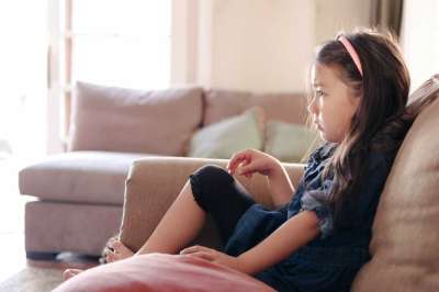 little girl watching tv on the couch