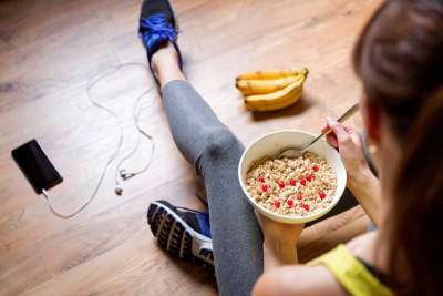 Young girl eating a oatmeal with berries after a workout 