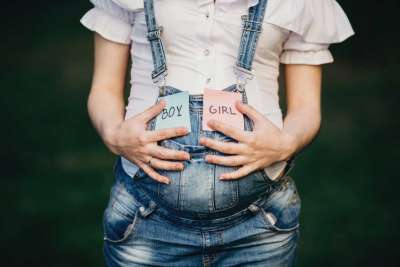 female hands at belly with with BOY and GIRL cards